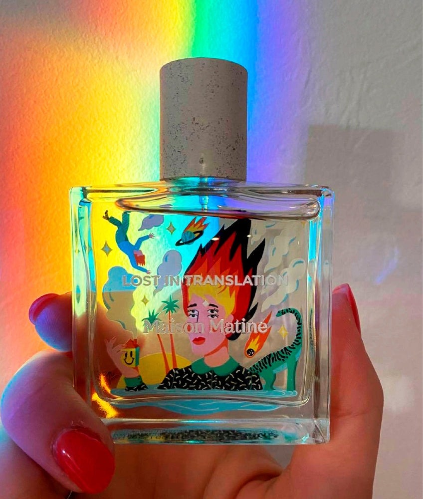 Hand holding Lost In Translation perfume under rainbow light