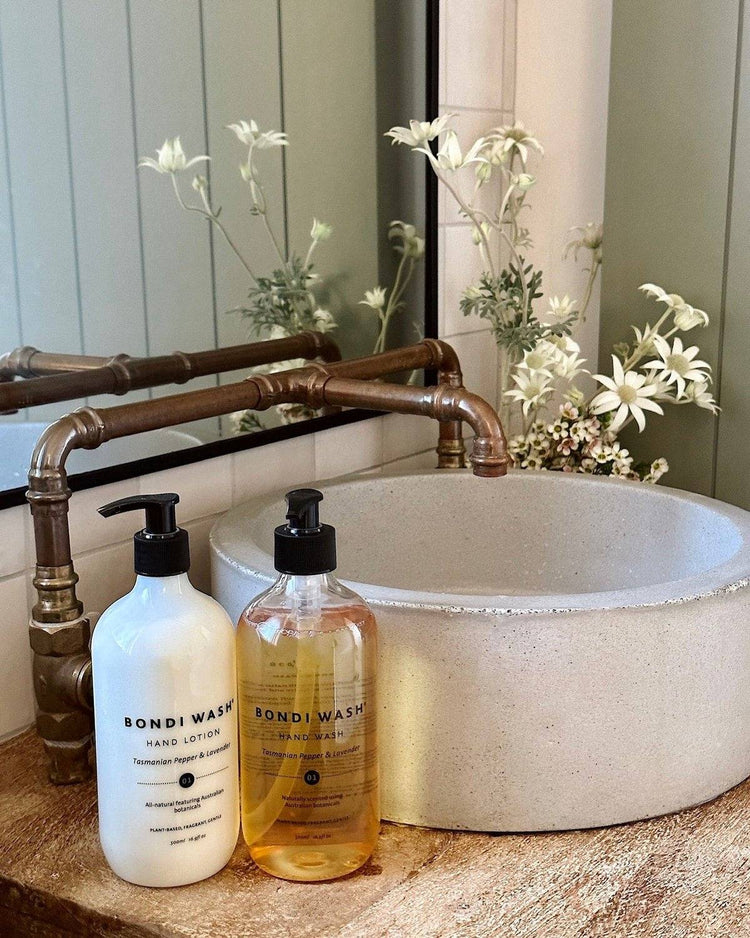 Bondi Wash Tasmanian Pepper Lavender hand lotion and wash set on stone sink with brass pipes