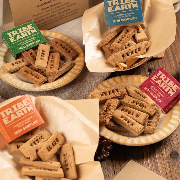 TRIBE EARTH incense mini sampler tins with four colored boxes and handmade textured sticks on rustic wooden background