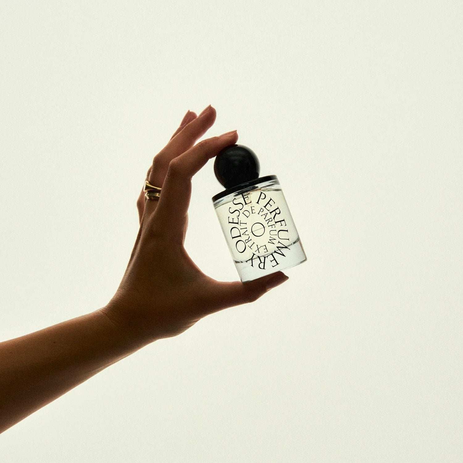 Odesse Perumera Extrait de Parfum collection bottle with matte black spherical cap held by hand