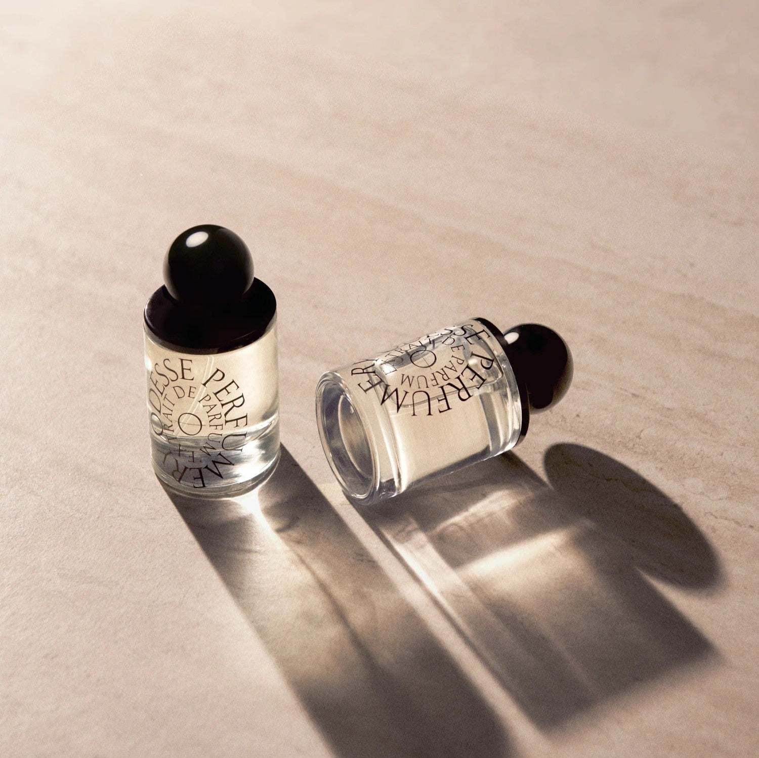 ODESSE perfume collection glass bottles with black spherical caps on beige stone
