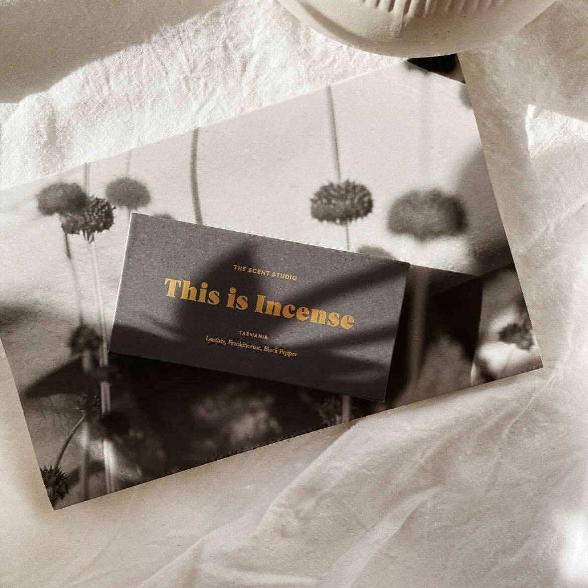 GENTLE HABITS Tasmanian incense flat lay with matte dark gray card, gold foil text, and botanical dandelion background