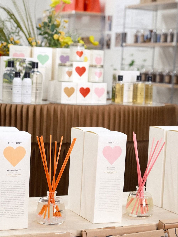 9to5 Studios Pinkmint and Tidy Kiss glass reed diffuser sets with pastel heart packaging on wood
