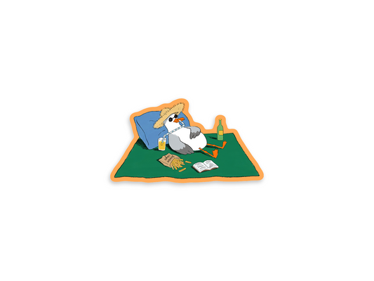 +61 Studio seagull sticker in a straw hat and sunglasses, reclining on a green mat with a drink and open book