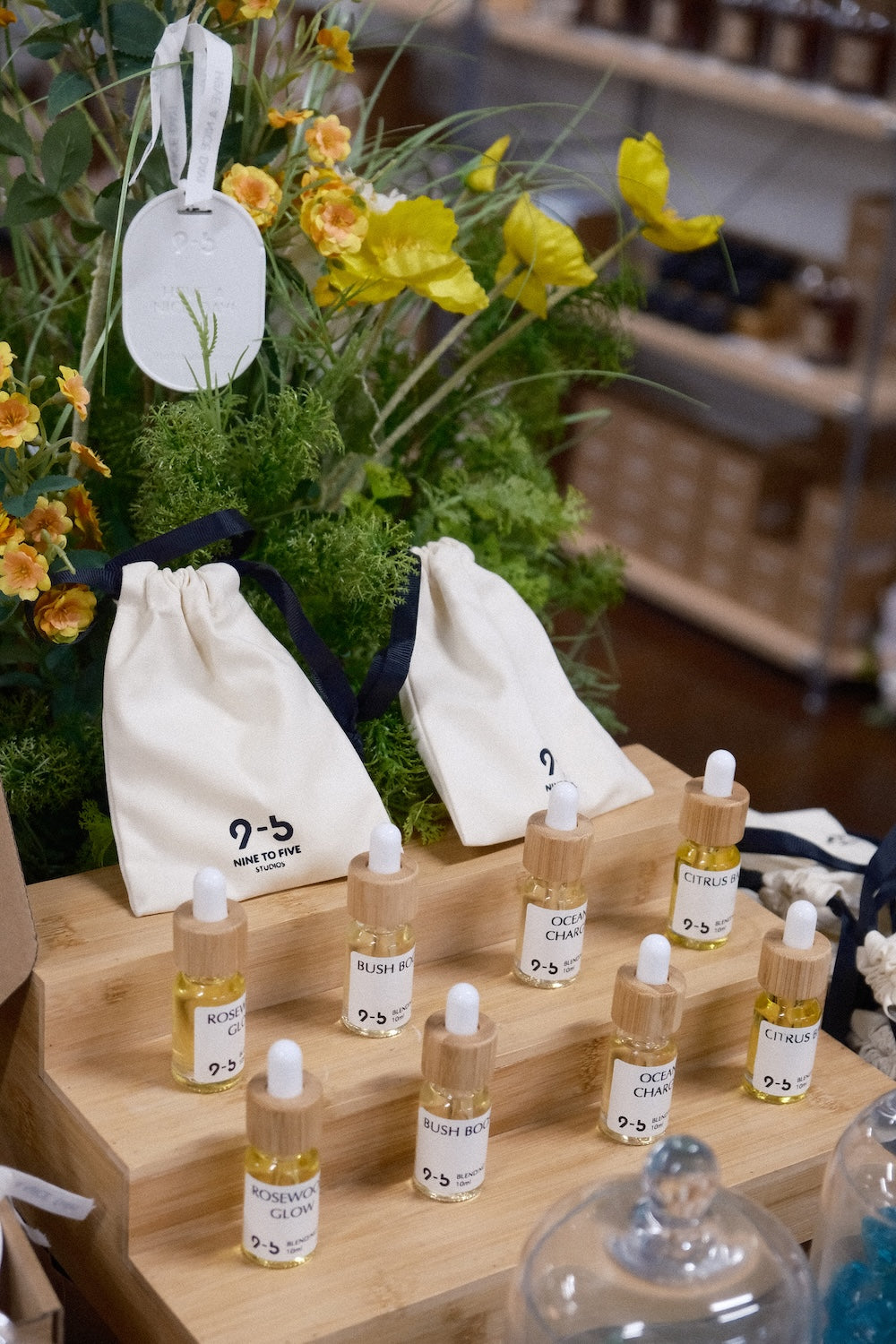 9to5 Studios fragrance oil display with pouches and greenery featuring Rosewood Glow and Ocean Charge