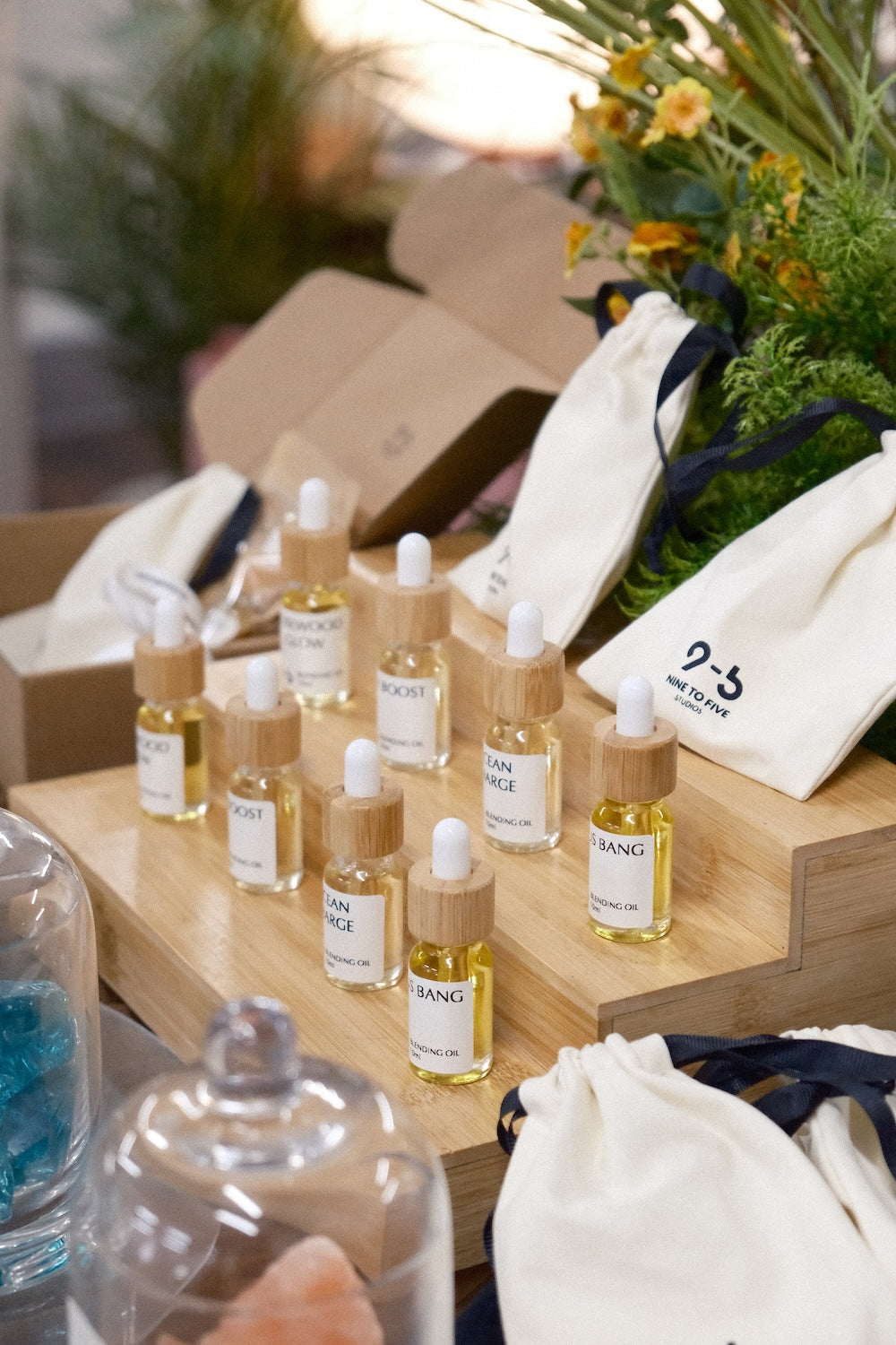 9to5 Studios tiered display of Blending Oil 10ml bottles with branded pouches and floral accents
