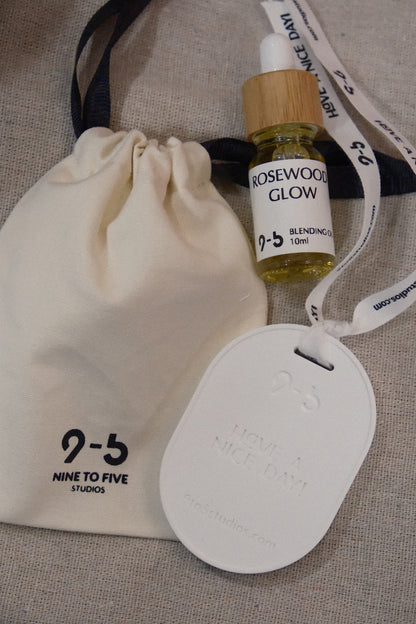 Rosewood Glow oil beside 9to5 Studios pouch on beige fabric