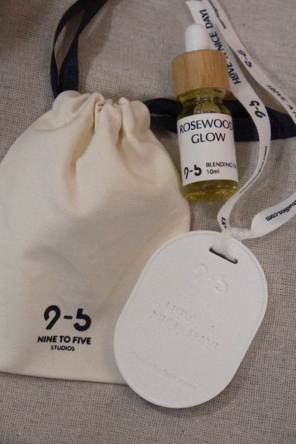 Rosewood Glow oil beside 9to5 Studios pouch on beige fabric