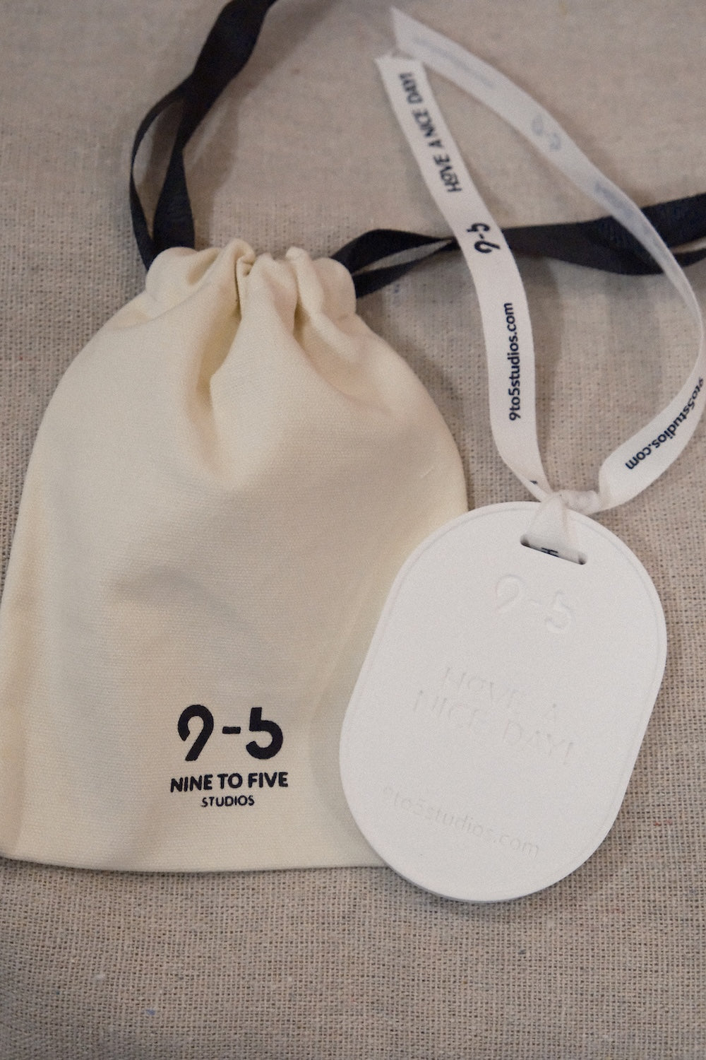 9to5 Studios white oval ceramic diffuser with ribbon tied to cream drawstring storage pouch