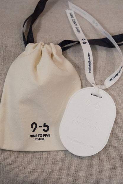 9to5 Studios white oval ceramic diffuser with ribbon tied to cream drawstring storage pouch