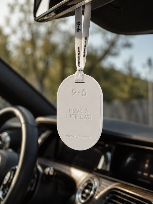 Metallic tag with 'Have a nice day!' message hanging from a car mirror.
