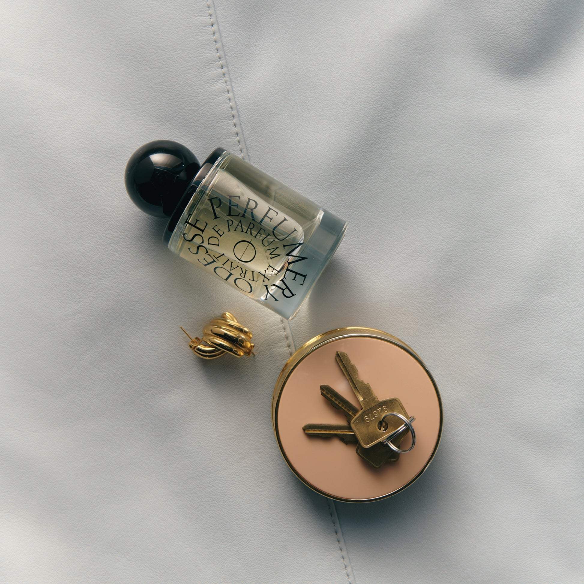 Odesse Crème Santal lifestyle flat-lay with gold hoop earring and keys at 9to5 Studios