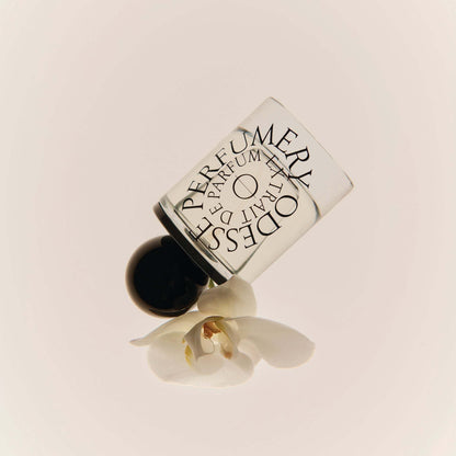 Odesse Deep Orchid perfume bottle beside white orchid flower at 9to5 Studios