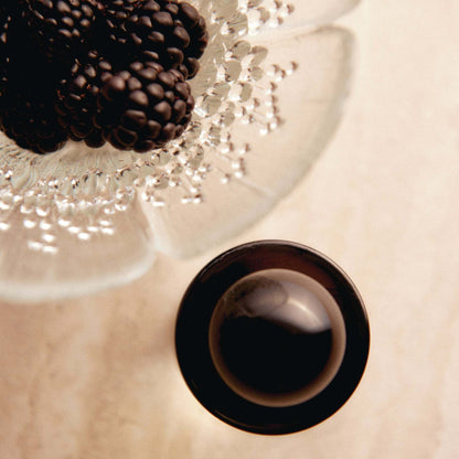 Close-up of dark blackberries in cut-glass bowl beside glossy black spherical cap from Odesse Hotel Jasmine