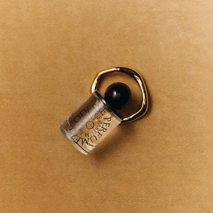 Odesse perfume bottle with gold ring accessory on tan background at 9to5 Studios