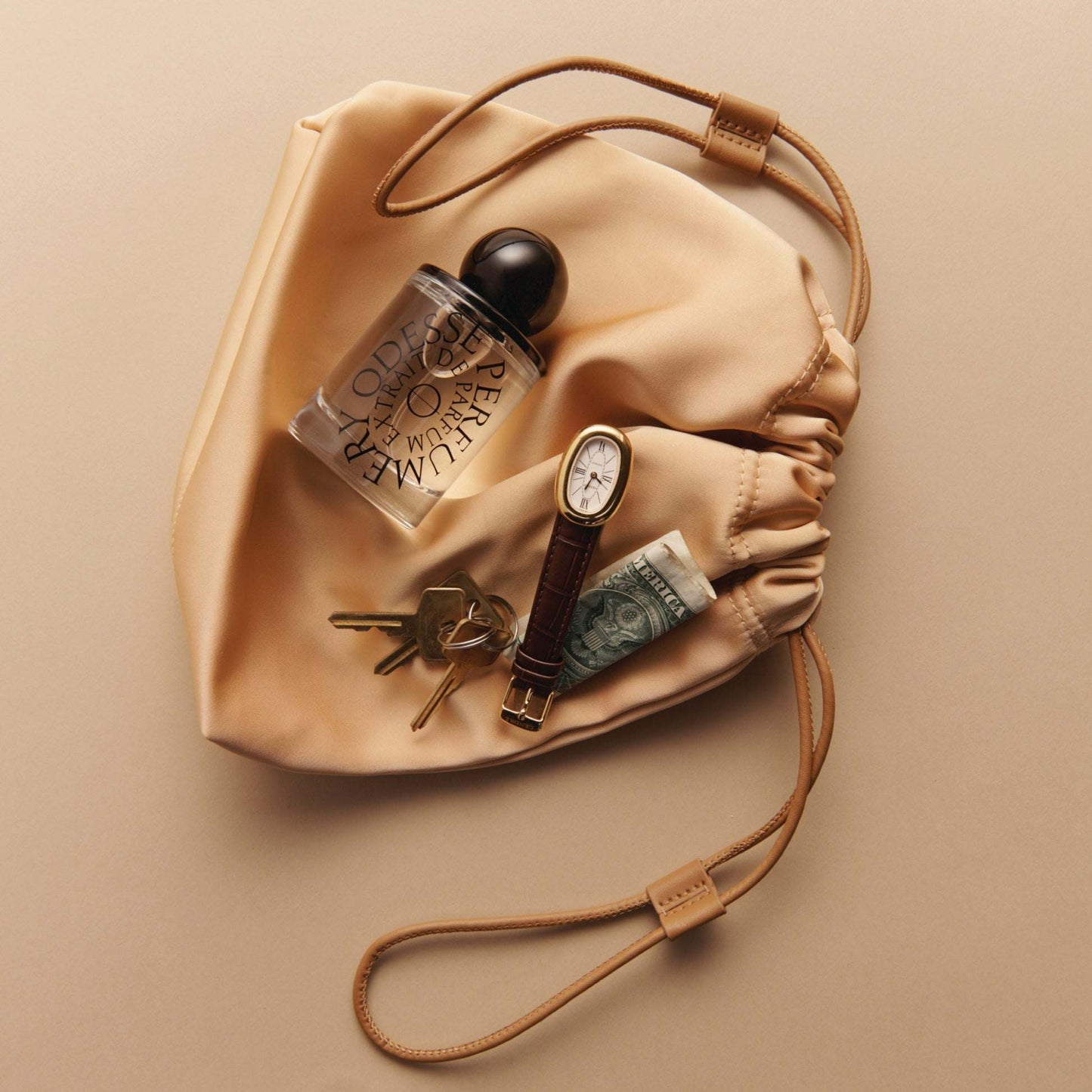 Odesse perfume in satin pouch with watch and keys lifestyle shot at 9to5 Studios
