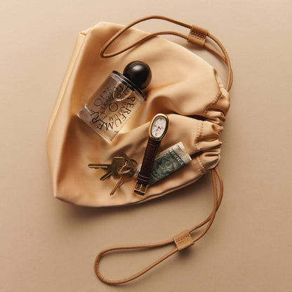 Odesse perfume in satin pouch with watch and keys lifestyle shot at 9to5 Studios