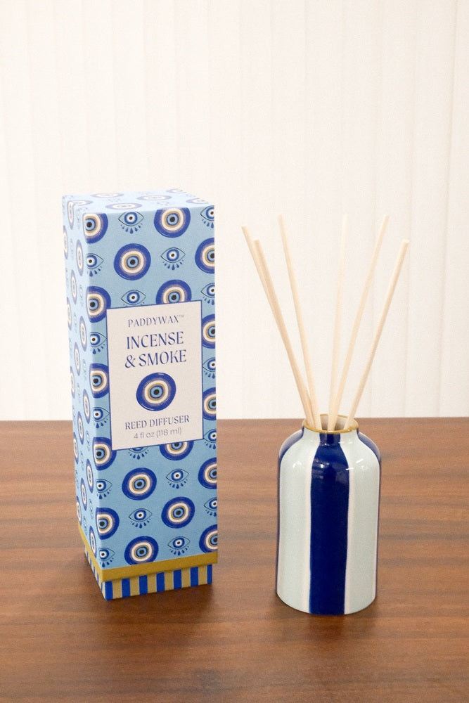 Side view of Paddywax Incense & Smoke reed diffuser showing white ceramic vessel with navy stripe