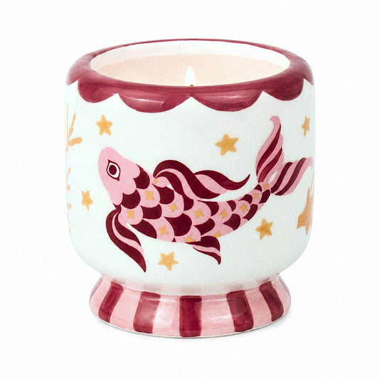 Lit Paddywax ceramic Koi candle featuring hand-painted pink maroon fish and gold seaweed