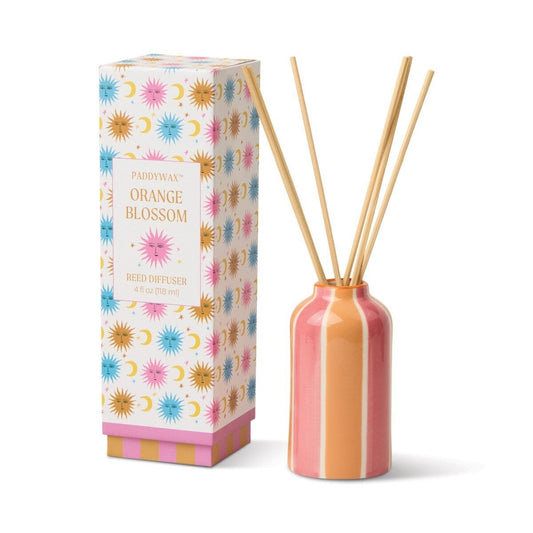 Paddywax Orange Blossom Reed Diffuser glossy ceramic vessel with reeds next to colorful sun moon retail box