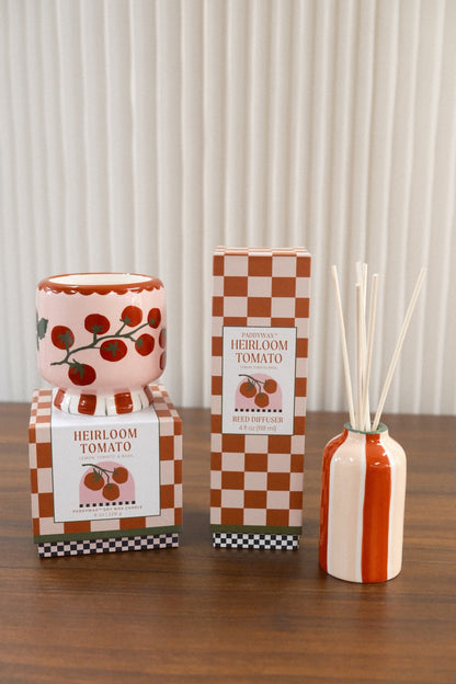 Paddywax Heirloom Tomato Reed Diffuser next to matching pink tomato candle on wooden surface