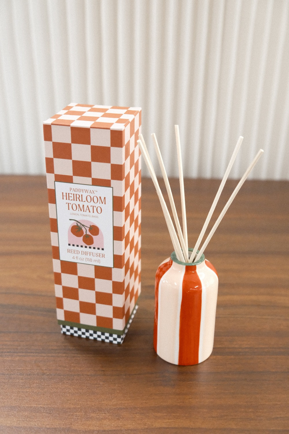 Paddywax A Dopo Tomato diffuser in glossy striped vase beside box on wood grain surface