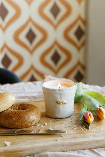 Lit Paddywax baguette-shaped soy wax candle on wooden board with brunch styling and warm ambient light