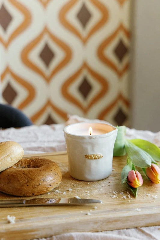 Lit Paddywax baguette-shaped soy wax candle on wooden board with brunch styling and warm ambient light