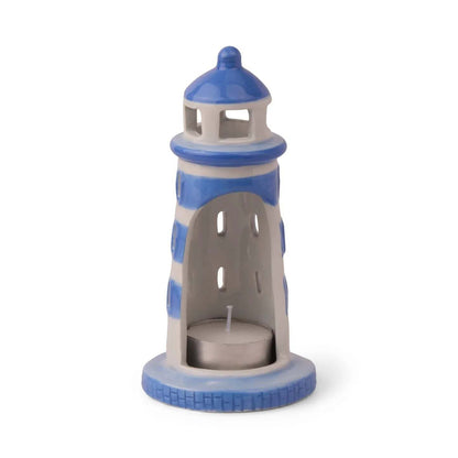 PADDYWAX blue ceramic lighthouse tea light holder with lit candle creating warm glow through vertical oval windows