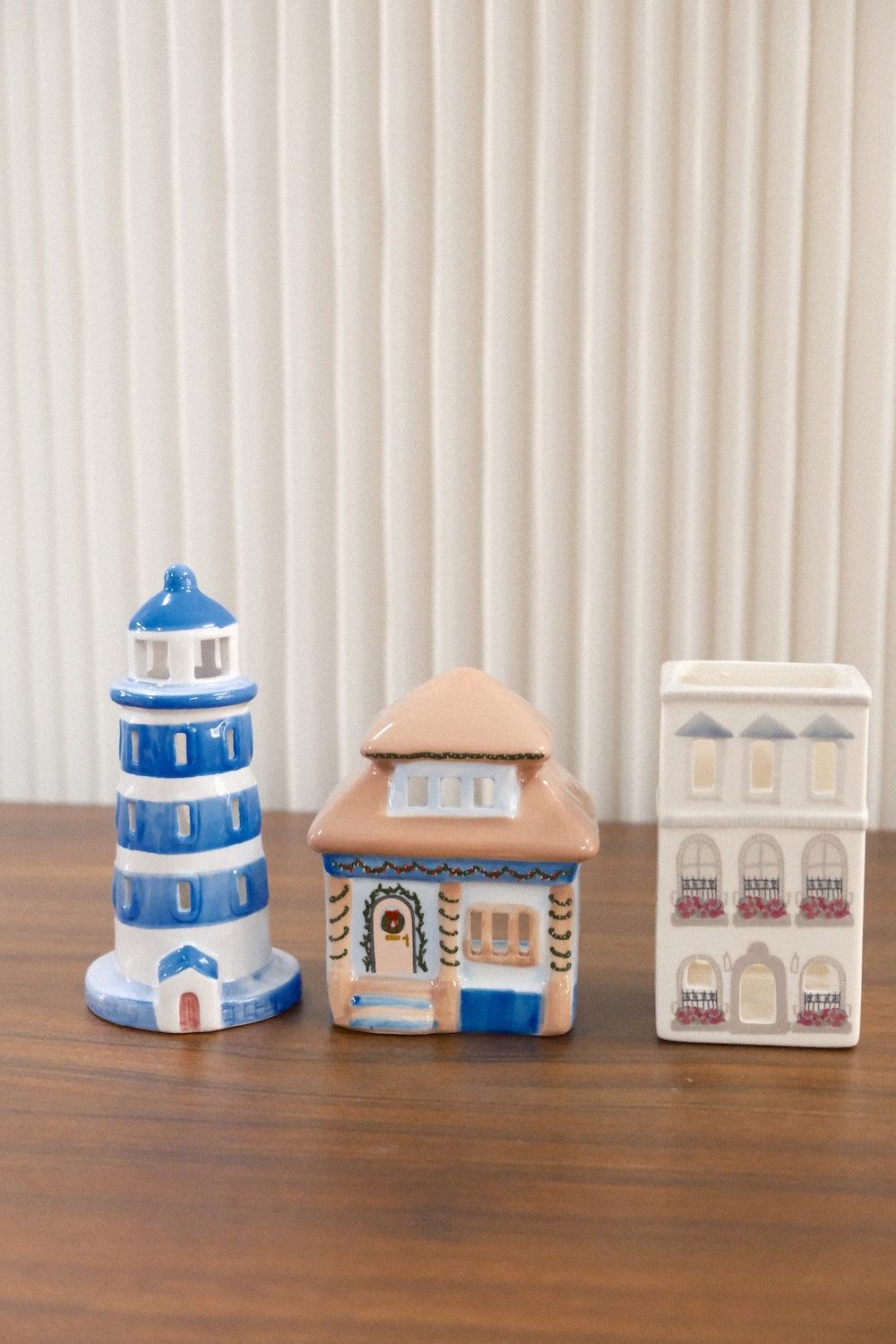 Set of three Paddywax ceramic decorative holders including lighthouse and multi-story building designs