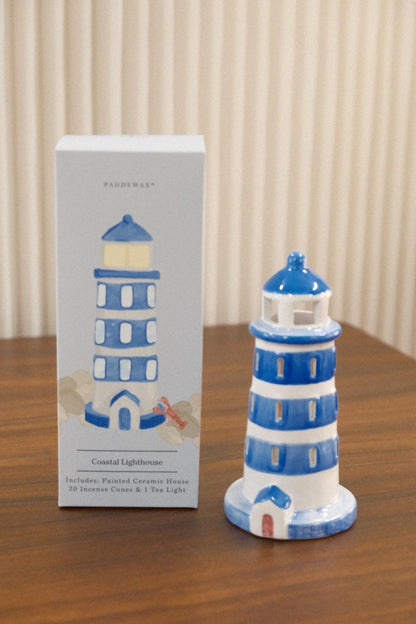 PADDYWAX Coastal Lighthouse ceramic incense holder on wood next to gray box featuring rounded top and red door accent