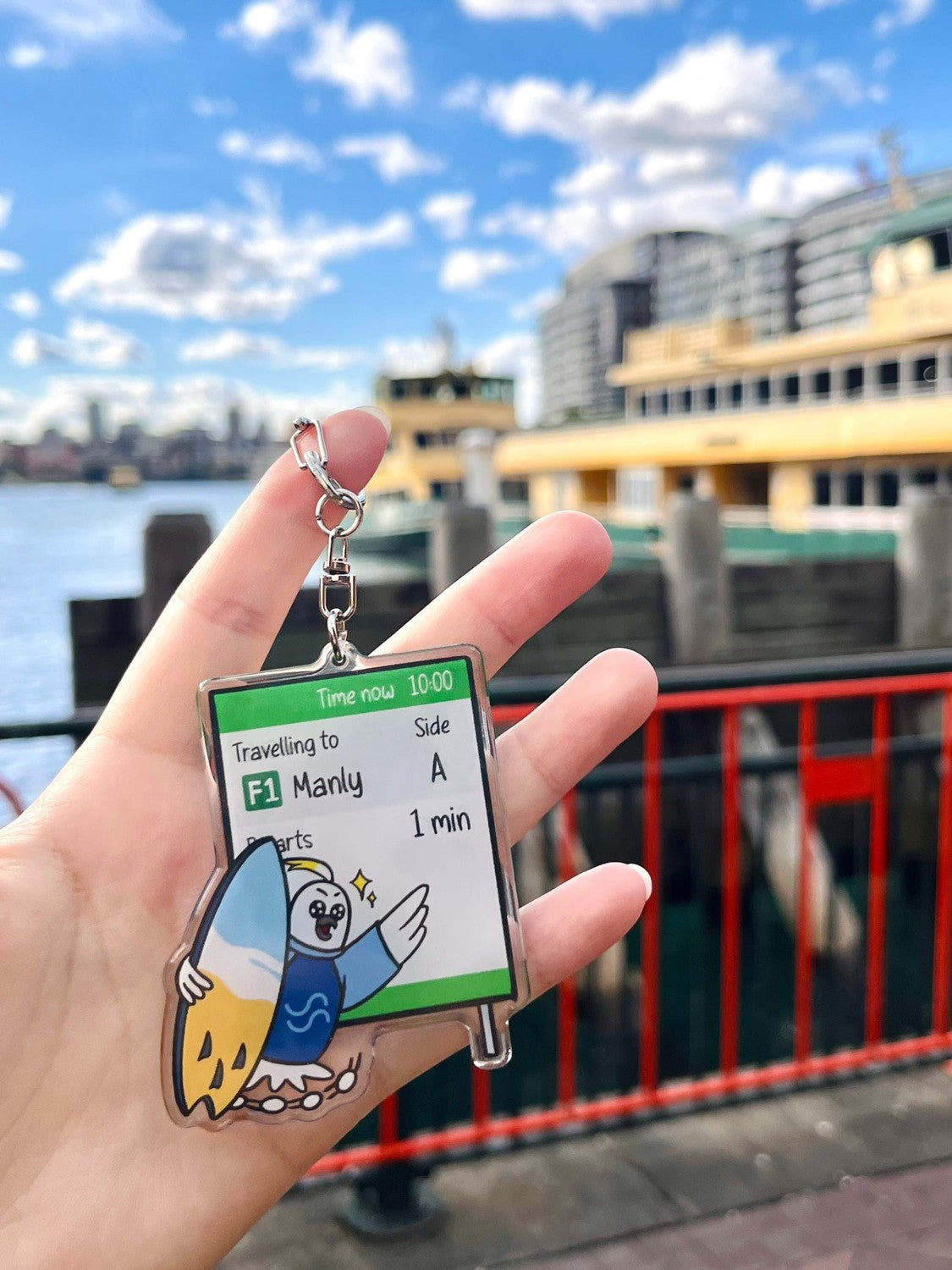 9to5 Studios Australian nature gift keychain against Sydney Harbour backdrop, glossy optical acrylic with cockatoo design