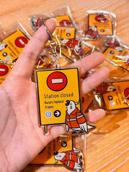 9to5 Studios yellow station closed keychain with crying cockatoo in orange vest
