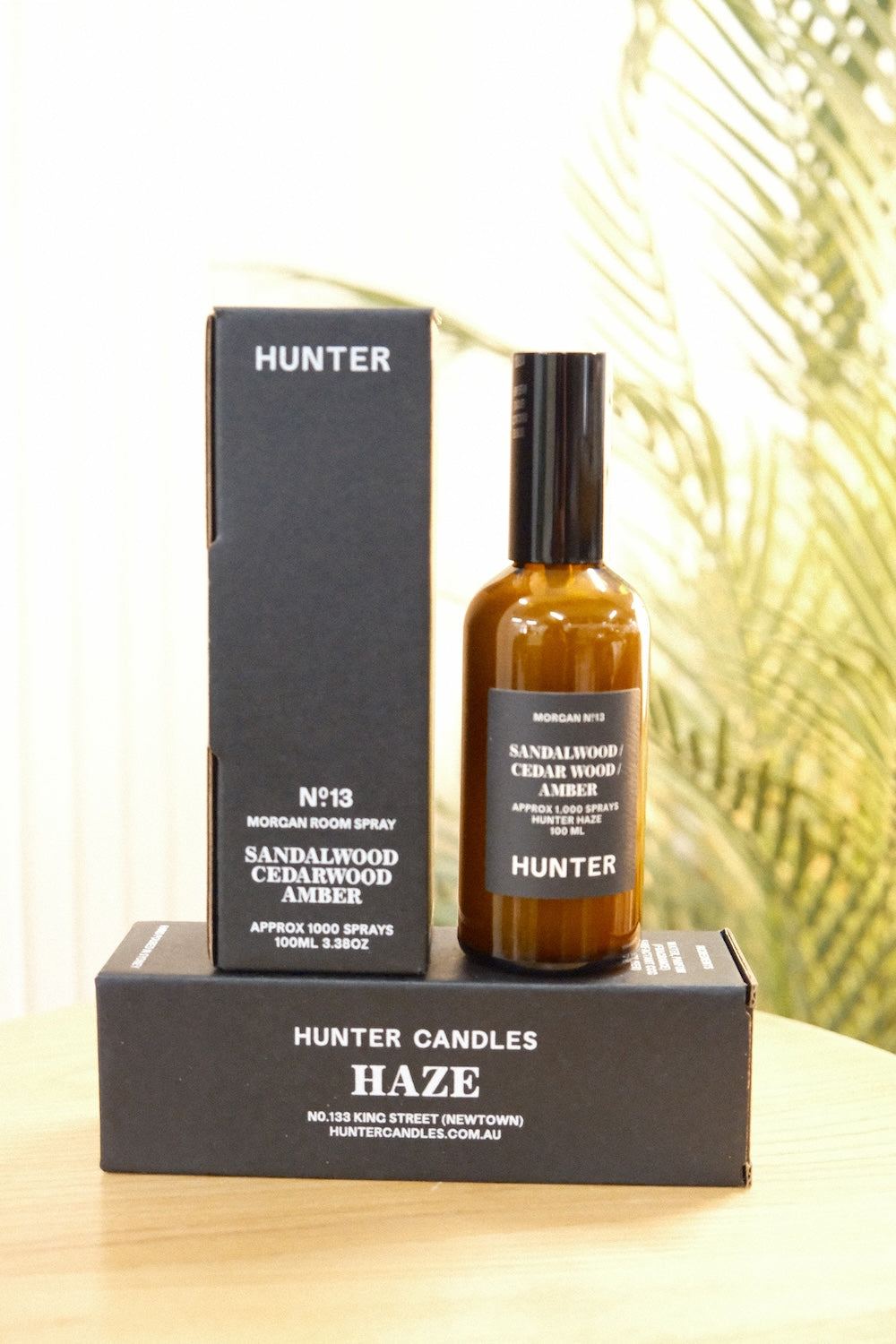 Hunter Candles The Haze room spray bottle and packaging box on wooden surface with palm leaves