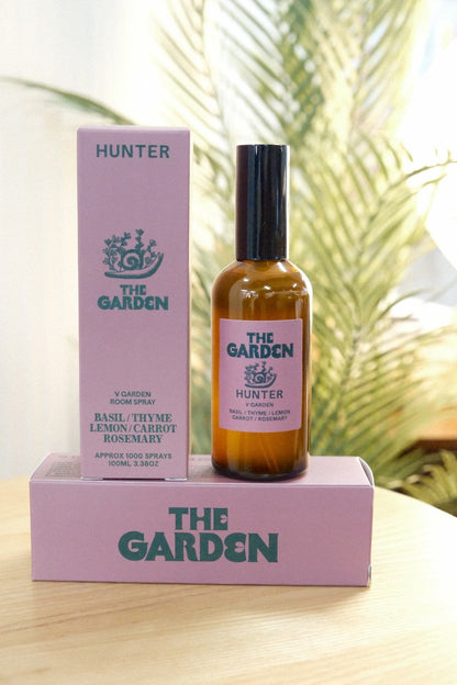 Amber glass room spray bottle on wooden surface with blurred green leaves
