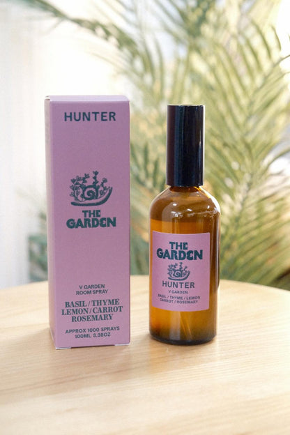 The Garden room spray bottle standing next to pink box with foliage background