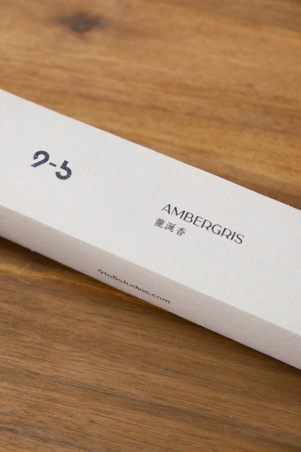 Macro view of off-white Ambergris incense box with fibrous texture and navy ink printing