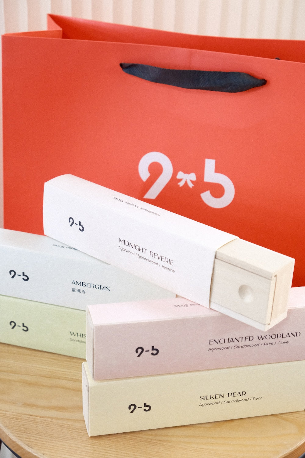 Pastel incense boxes including Enchanted Woodland on wooden table with orange shopping bag