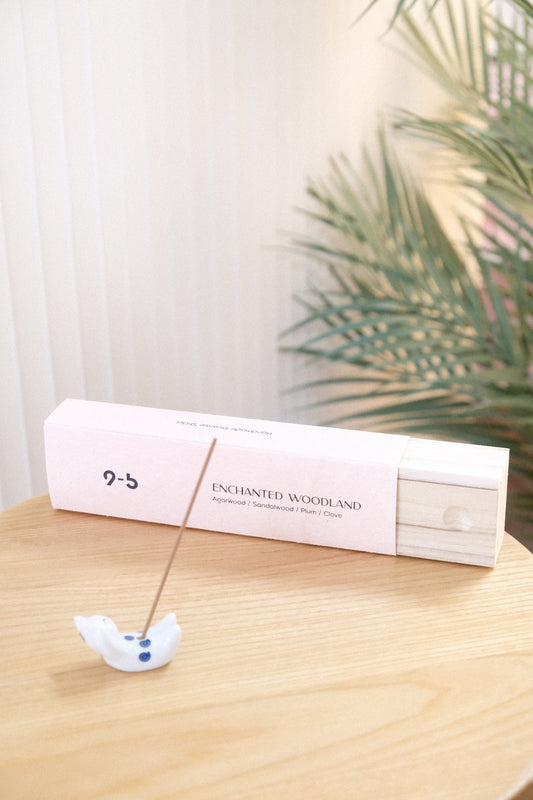 Lit incense stick in ceramic bird holder next to pink Enchanted Woodland box