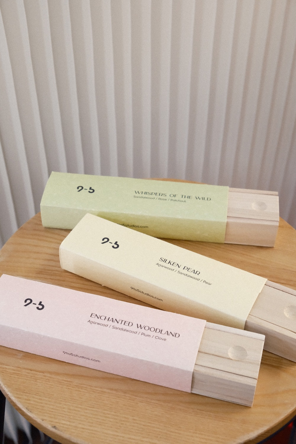 Three pastel incense boxes with exposed wood drawers arranged on wooden stool