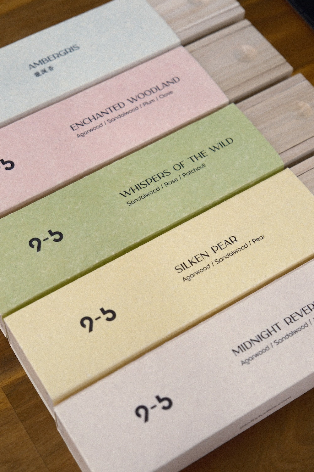 Overhead view of four stacked incense packages with matte sleeves and wood trays