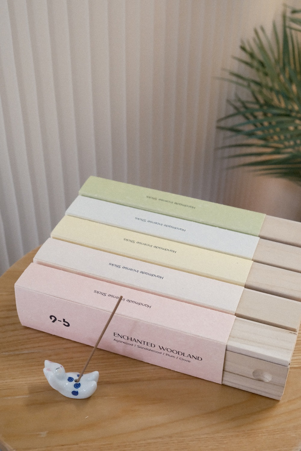 Handmade incense sticks with ceramic animal holder displaying Enchanted Woodland box and single brown stick on wooden surface
