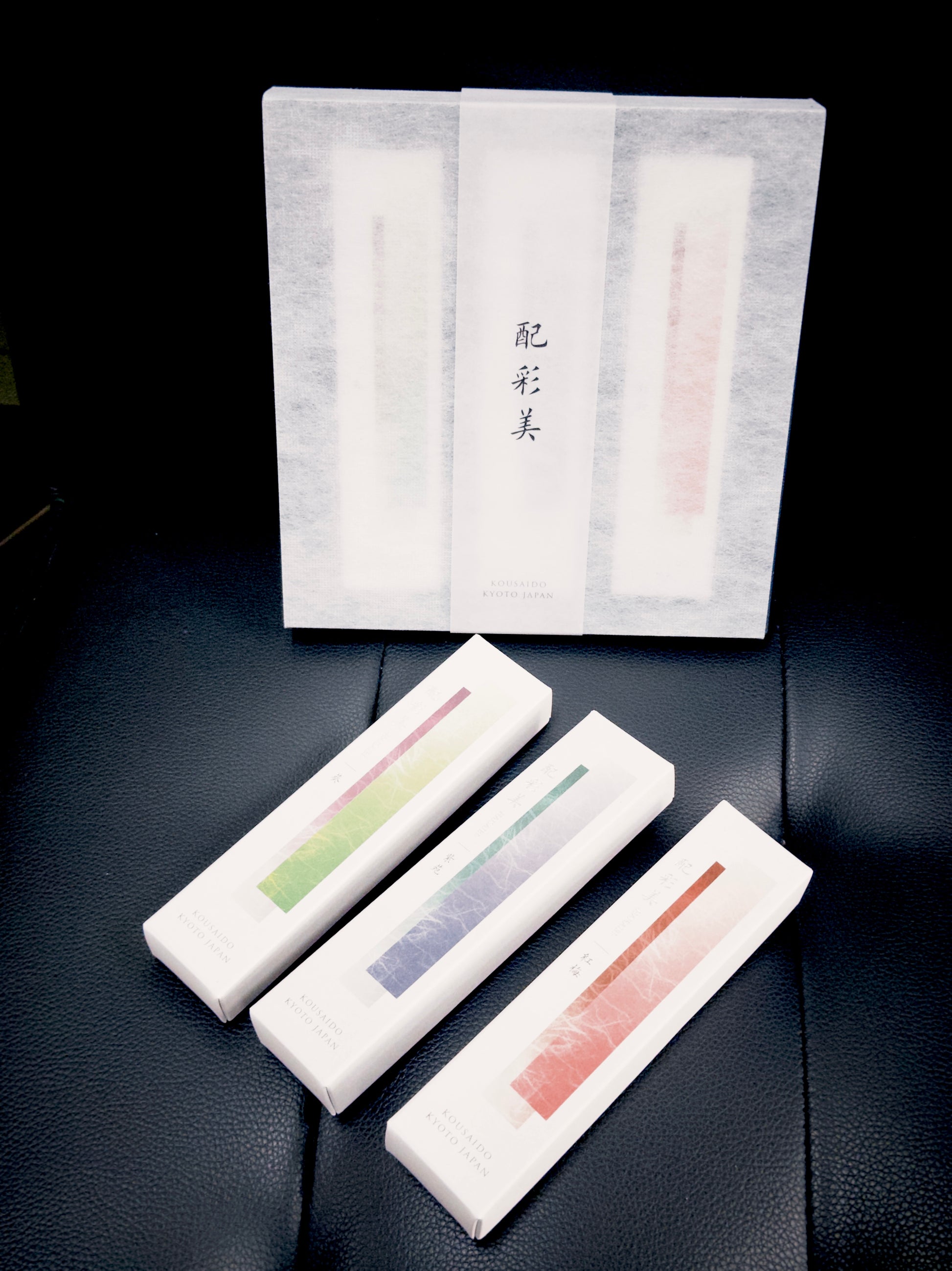 Colored Kousaido incense sticks on leather beside semi-transparent gift box at 9to5 Studios
