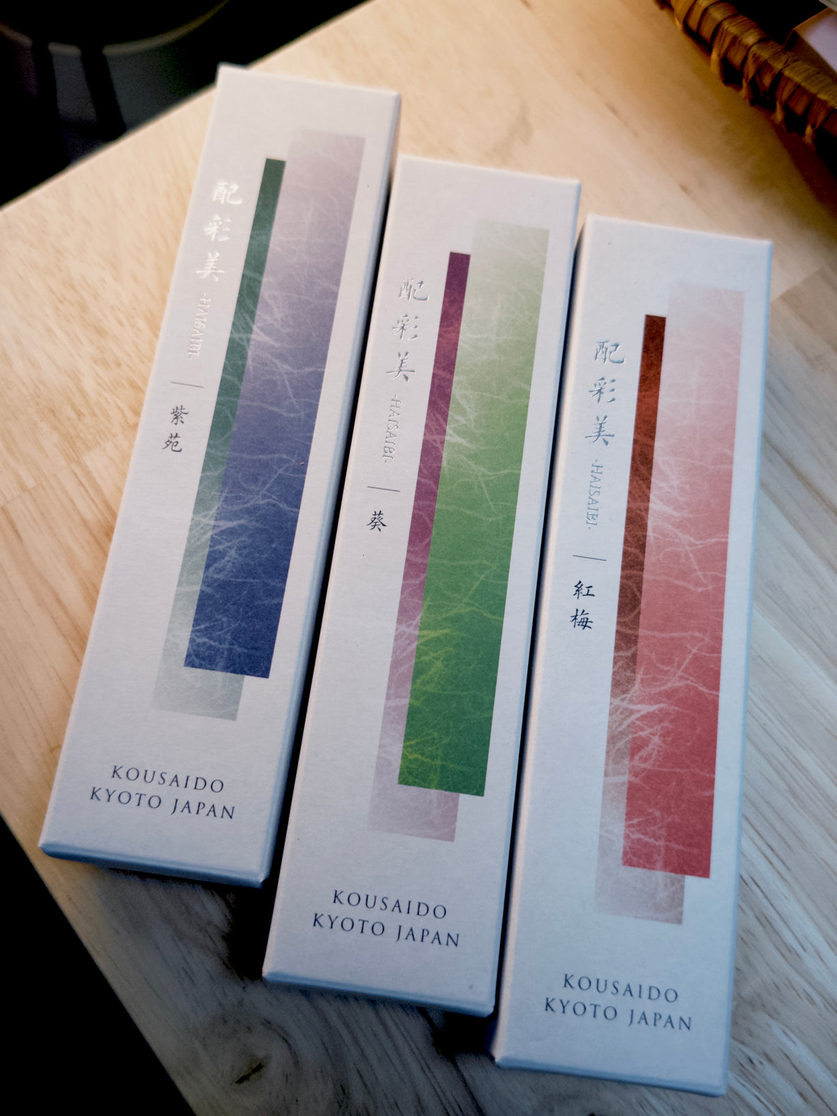 Three Kousaido incense boxes with layered color gradients on wood by 9to5 Studios