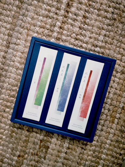 Open navy blue Kousaido incense gift set showing colorful striped packs on rug at 9to5 Studios