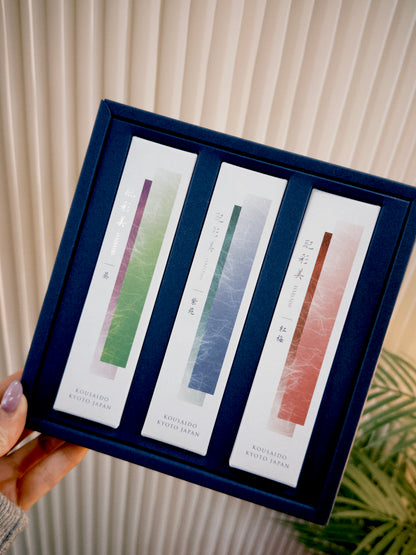 Hand holding open navy Kousaido incense gift set with gradient packs and calligraphy at 9to5 Studios