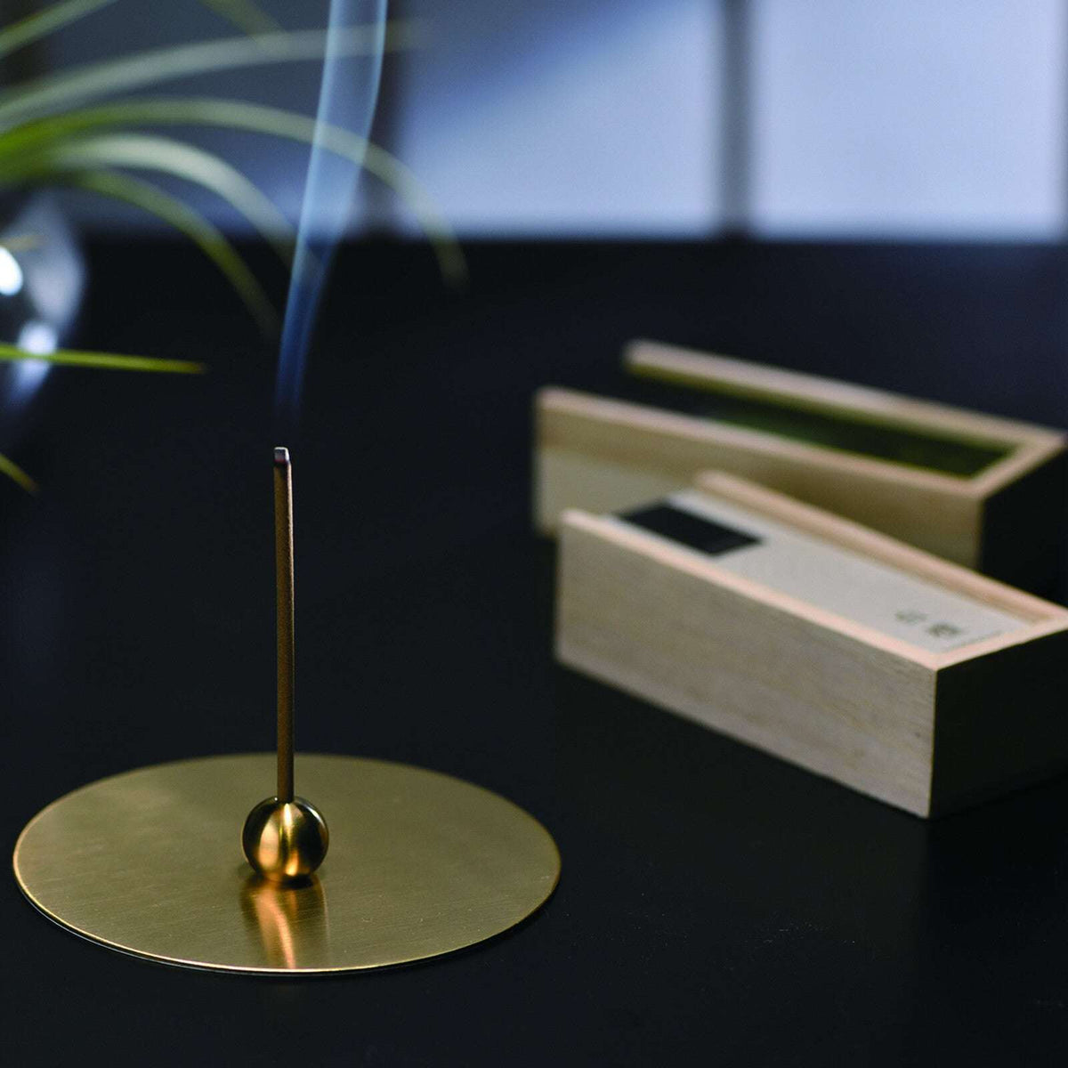 Lit Kousaido Hitotoki Magnolia Incense Stick burning in brass holder emitting smoke for mindful relaxation rituals at 9to5 Studios