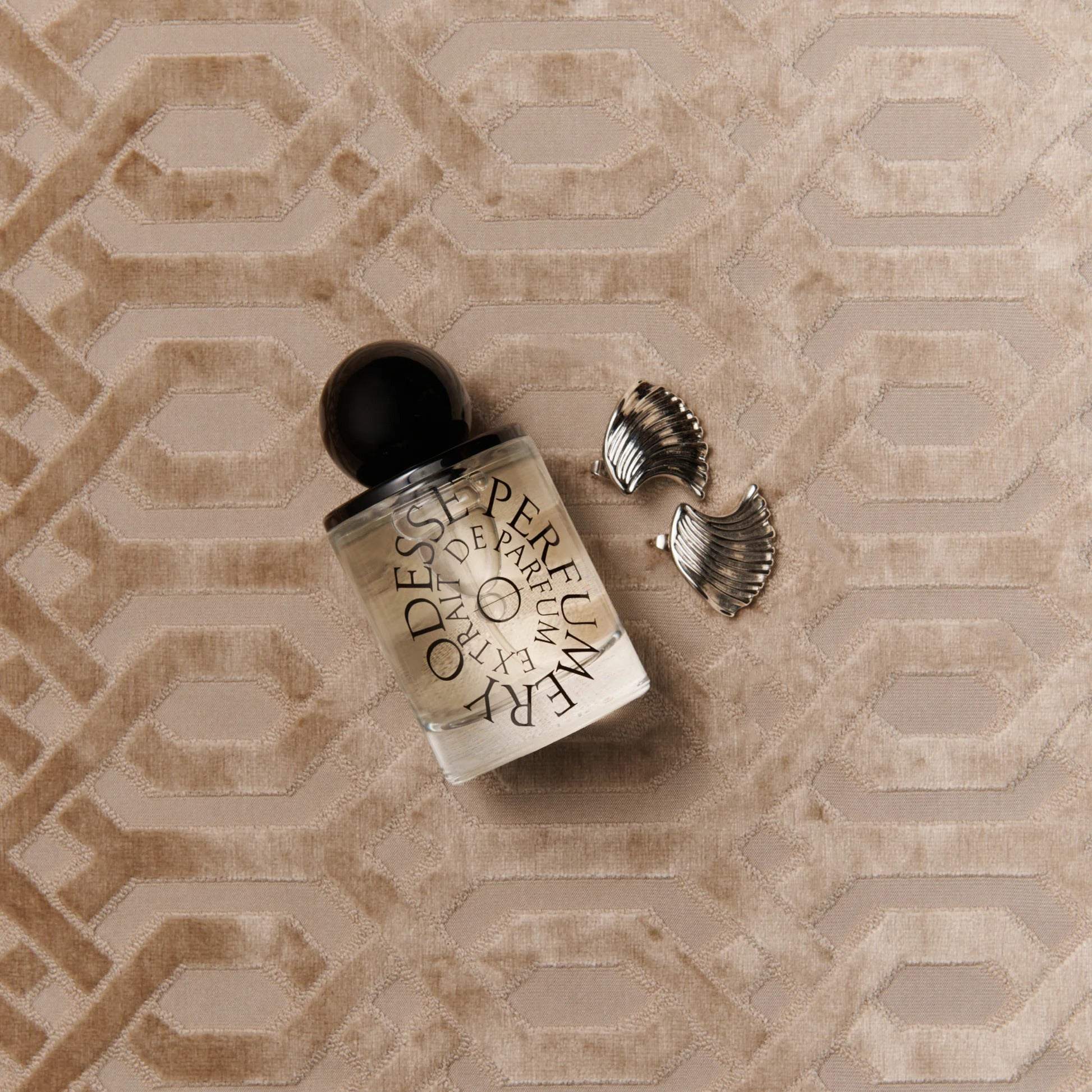Odesse Morning Skin perfume bottle flat lay with silver earrings on velvet
