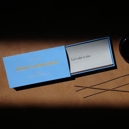 Open blue Gentle Habits incense box revealing silver card and brown sticks on warm surface by 9to5 Studios