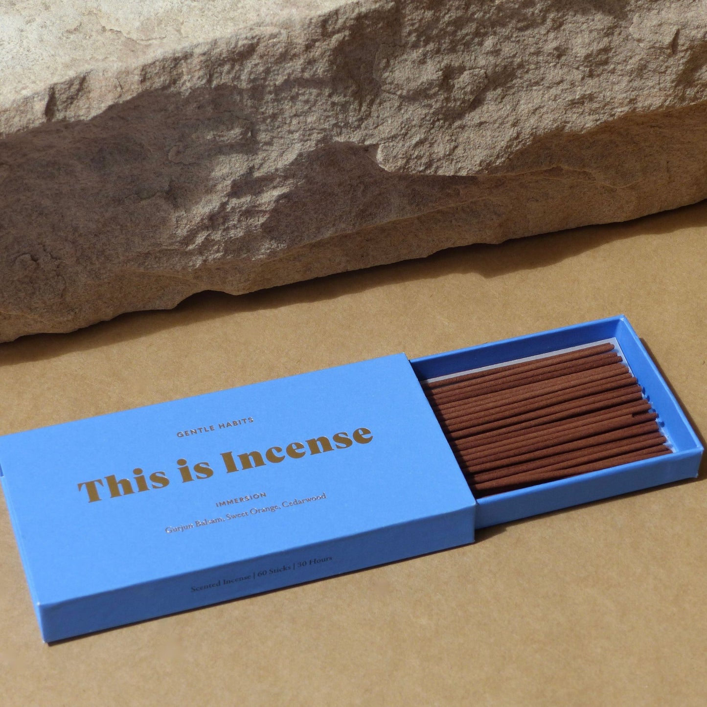 Close-up of open blue incense box with neat rows of sticks and natural stone element by 9to5 Studios